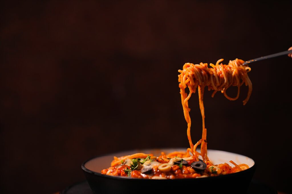A plate of stir-fried noodles served with fresh vegetables and flavorful seasonings at Spice Aromas Open Air Restaurant near Munnar.