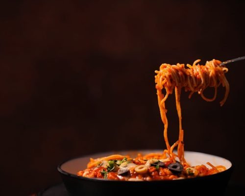 A plate of stir-fried noodles served with fresh vegetables and flavorful seasonings at Spice Aromas Open Air Restaurant near Munnar.